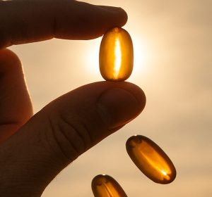 Hand holding vitamin d gel pill up to sun