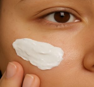 Woman applying adapalene cream to face